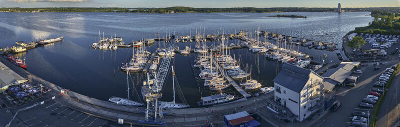 Schleswig Germany 01 July 2026 Aerial view of Schleswig yacht harbour on the Schlei featuring a harbor crane sailboats moored at the docks and surrounding waterfront buildings.
