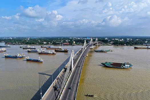 Aerial view of the Shah Amanat Bridge spanning the Karnaphuli River with numerous cargo ships and vessels navigating the waterway in Chattogram Chittagong Division Bangladesh.