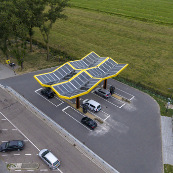 Aerial view of the Fastned charging station with solar panel roof parked electric vehicles and surrounding green landscape in Beesd Gelderland Netherlands. Aerial view of the Fastned charging station with solar panel roof parked electric vehicles and surrounding green landscape in Beesd Gelderland Netherlands.