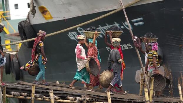 View of workers carrying coal baskets from a ship Bangladesh. View of workers carrying coal baskets from a ship Bangladesh.