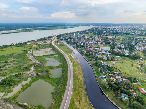 Aerial view of Kalurghat New River view Road running alongside the Karnaphuli River with urban development and green fields in Chattogram Chittagong Division Bangladesh.