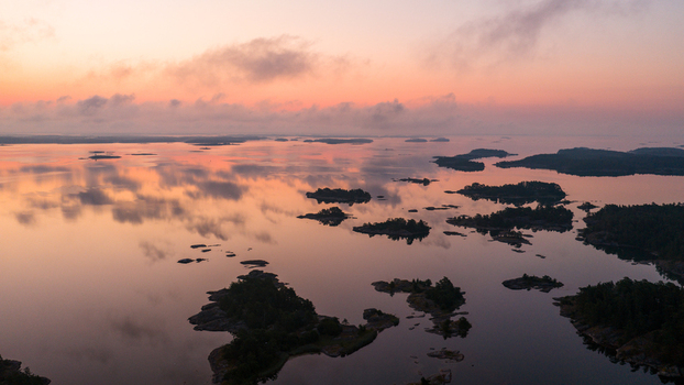 Aerial view of the small islands and calm waters of Archipelago National Park during a pink sunrise in Hiittinen Southwest Finland Finland.