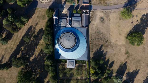 Aerial view of the Wellcome Genome Campus featuring its distinctive circular glass roof surrounded by lush parkland and trees in Hinxton England United Kingdom. Aerial view of the Wellcome Genome Campus featuring its distinctive circular glass roof surrounded by lush parkland and trees in Hinxton England United Kingdom.