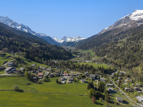 Saint Gervais les Bains France 30 April 2026 Aerial view of the alpine village nestled in a lush green valley surrounded by pine forests and snow capped mountain peaks under a clear blue sky.