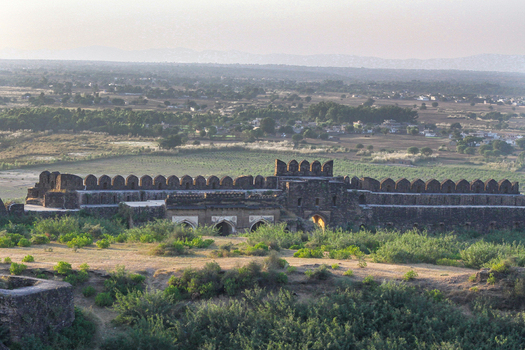 View of Rohtas Fort with its historic stone walls and arched gateways set against a landscape of green fields and distant plains in Dina Punjab Pakistan. View of Rohtas Fort with its historic stone walls and arched gateways set against a landscape of green fields and distant plains in Dina Punjab Pakistan.