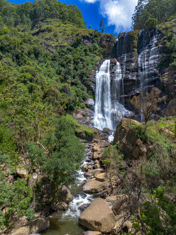 Aerial view of Bomburu Ella Waterfall cascading down rocky cliffs surrounded by lush green forest and trees in Nuwara Eliya Central Province Sri Lanka. Aerial view of Bomburu Ella Waterfall cascading down rocky cliffs surrounded by lush green forest and trees in Nuwara Eliya Central Province Sri Lanka.