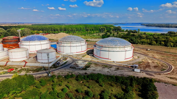 Aerial view of large white fuel tanks with domed roofs situated in an industrial facility near a river surrounded by lush greenery and trees in Kovin Vojvodina Serbia. Aerial view of large white fuel tanks with domed roofs situated in an industrial facility near a river surrounded by lush greenery and trees in Kovin Vojvodina Serbia.