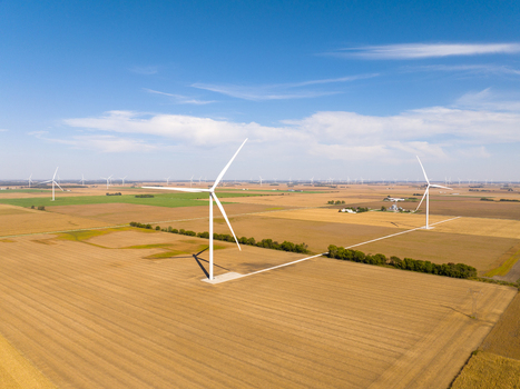 Aerial view of wind turbines in a vast agricultural field under a clear blue sky in Wolcott Indiana United States.