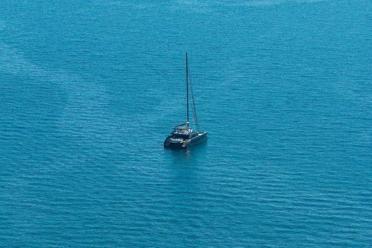 Aerial view of a modern catamaran sailing in the deep blue Mediterranean Sea near Antibes Provence Alpes Cote d Azur France. Aerial view of a modern catamaran sailing in the deep blue Mediterranean Sea near Antibes Provence Alpes Cote d Azur France.