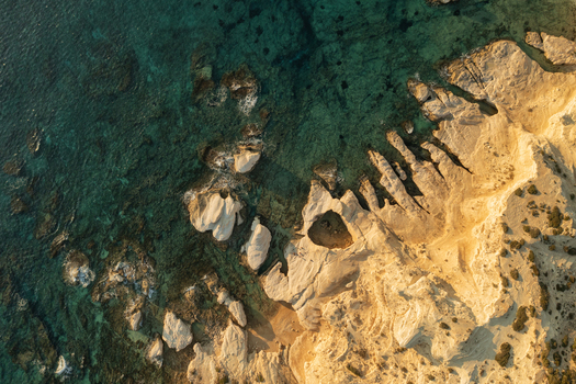 Aerial view of the rugged coastline where the golden cliffs meet the clear turquoise sea Fira Thira Greece. Aerial view of the rugged coastline where the golden cliffs meet the clear turquoise sea Fira Thira Greece.