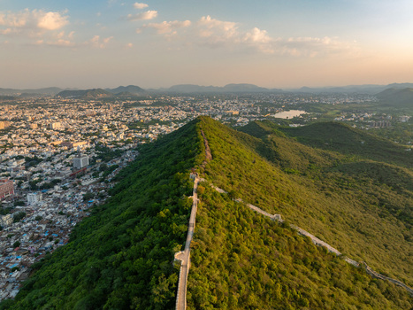 Aerial view of the historic stone wall on a lush green ridge overlooking the city of Udaipur Rajasthan India.