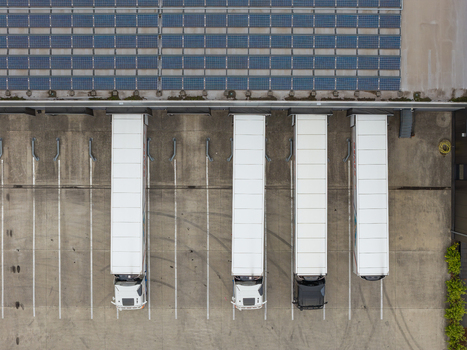 Aerial view of semi trucks parked at a logistics distribution center with solar panels on the warehouse roof in Genk Flanders Belgium. Aerial view of semi trucks parked at a logistics distribution center with solar panels on the warehouse roof in Genk Flanders Belgium.