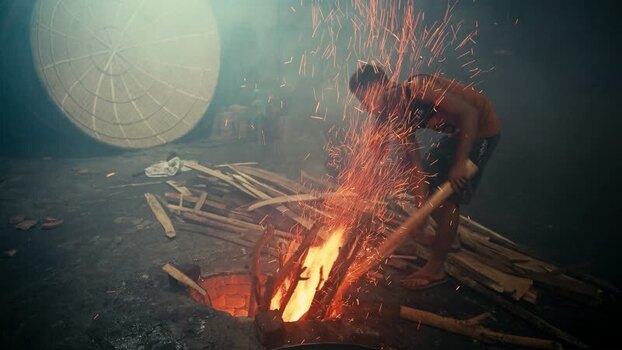 View of a worker tending a fire in a workshop in Bangladesh. View of a worker tending a fire in a workshop in Bangladesh.