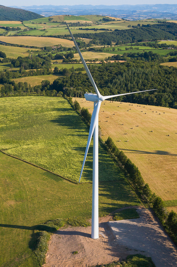 Aerial view of a solitary wind turbine standing tall amidst a patchwork of golden fields and verdant forests under a tranquil sky Salles Curan Occitanie France. Aerial view of a solitary wind turbine standing tall amidst a patchwork of golden fields and verdant forests under a tranquil sky Salles Curan Occitanie France.
