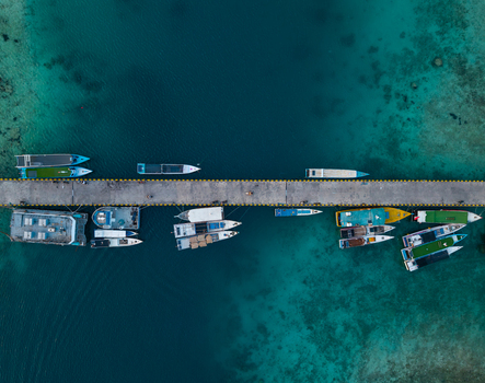 Aerial view of Karimunjawa dockyard with various boats moored along the concrete pier surrounded by clear turquoise tropical waters in Karimunjawa Jawa Tengah Indonesia. Aerial view of Karimunjawa dockyard with various boats moored along the concrete pier surrounded by clear turquoise tropical waters in Karimunjawa Jawa Tengah Indonesia.