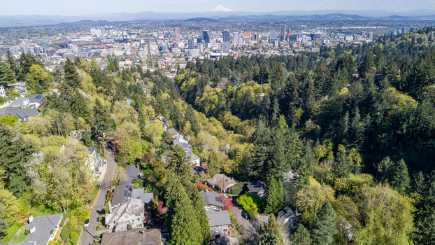 Aerial view of Northwest Imperial Terrace residential houses on a lush green hillside overlooking the Portland skyline and Mount Hood in Portland Oregon United States. Aerial view of Northwest Imperial Terrace residential houses on a lush green hillside overlooking the Portland skyline and Mount Hood in Portland Oregon United States.