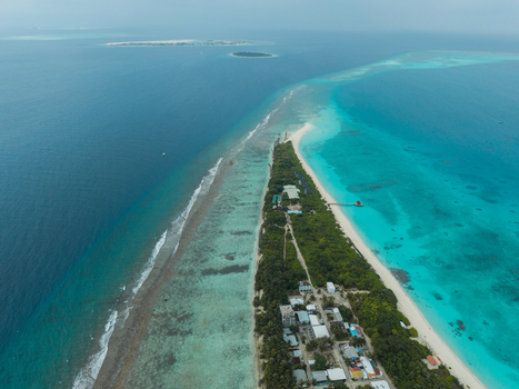 Aerial view of the narrow island with lush green vegetation contrasting against the surrounding turquoise waters Vashafaru Island Thiladhummathi Atoll Maldives. Aerial view of the narrow island with lush green vegetation contrasting against the surrounding turquoise waters Vashafaru Island Thiladhummathi Atoll Maldives.