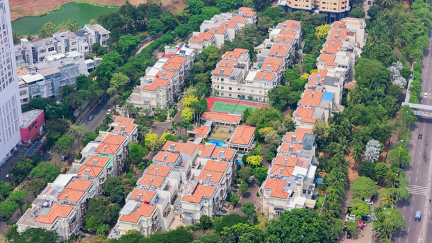 Aerial view of a residential complex with rows of houses featuring orange tiled roofs a tennis court and lush green trees in Jakarta Indonesia. Aerial view of a residential complex with rows of houses featuring orange tiled roofs a tennis court and lush green trees in Jakarta Indonesia.
