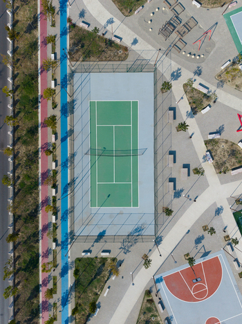 Aerial view of a tennis court in a public park with a basketball court walking paths and trees in Berat Berat County Albania.