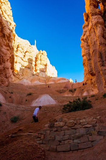 View of Bryce Canyon National Park with red rock hoodoos and a person walking on a trail in Utah United States.