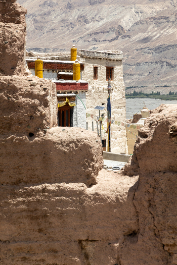 View of Charasa Gonpa with its white washed walls yellow pillars and prayer flags set against a rugged mountain landscape in Charasa Ladakh India.