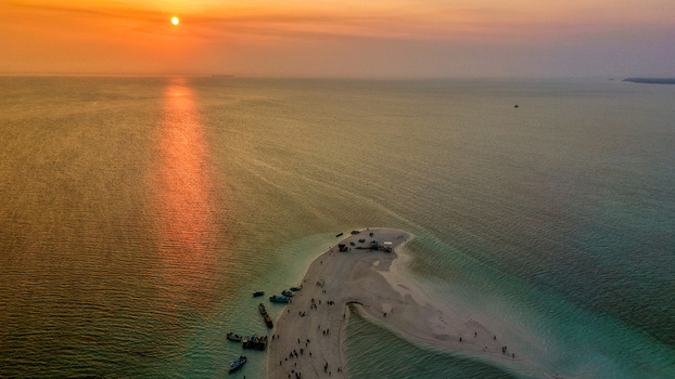 Aerial view of Pulau Gusung Sanggalau a small sandy island surrounded by turquoise waters coral reefs and clear blue sky in Kecamatan Pulau Derawan Kalimantan Timur Indonesia. Aerial view of Pulau Gusung Sanggalau a small sandy island surrounded by turquoise waters coral reefs and clear blue sky in Kecamatan Pulau Derawan Kalimantan Timur Indonesia.