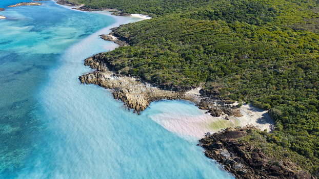 Aerial view of Chance Bay featuring turquoise waters rocky coastline and dense green forest in Whitsundays Queensland Australia. Aerial view of Chance Bay featuring turquoise waters rocky coastline and dense green forest in Whitsundays Queensland Australia.