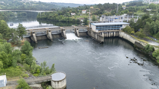 Aerial view of the Subestacion Electrica Velle and dam on the Minho River with water flowing through the spillway and lush green banks Ourense Ourense Spain.