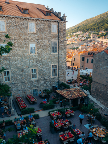 View of people dining at an outdoor restaurant terrace surrounded by historic stone buildings in Dubrovnik Old Town Dubrovnik Dubrovnik Neretva County Croatia. View of people dining at an outdoor restaurant terrace surrounded by historic stone buildings in Dubrovnik Old Town Dubrovnik Dubrovnik Neretva County Croatia.