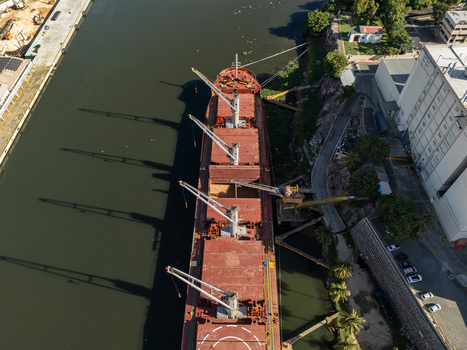 Aerial view of a large cargo ship docked on the Rio Ozama showing deck cranes and industrial waterfront in Santo Domingo Santo Domingo Dominican Republic.