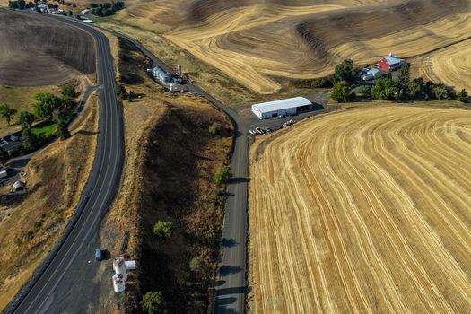 Aerial view of the rolling hills of the Palouse region featuring golden harvested fields a farmstead with a red barn and winding rural roads in Palouse Washington United States. Aerial view of the rolling hills of the Palouse region featuring golden harvested fields a farmstead with a red barn and winding rural roads in Palouse Washington United States.