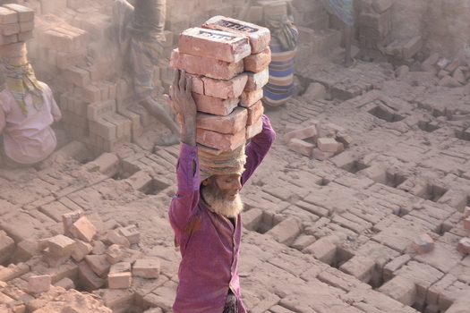 Kushtia District Khulna Division Bangladesh 28 November 2020 View of a man carrying a heavy stack of red bricks on his head at a brickyard. Kushtia District Khulna Division Bangladesh 28 November 2020 View of a man carrying a heavy stack of red bricks on his head at a brickyard.