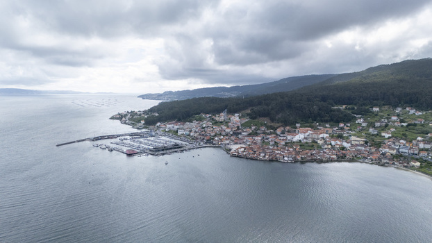 Aerial view of the historic coastal village of Combarro featuring its marina traditional stone architecture and green hills under a cloudy sky in Combarro Pontevedra Spain. Aerial view of the historic coastal village of Combarro featuring its marina traditional stone architecture and green hills under a cloudy sky in Combarro Pontevedra Spain.