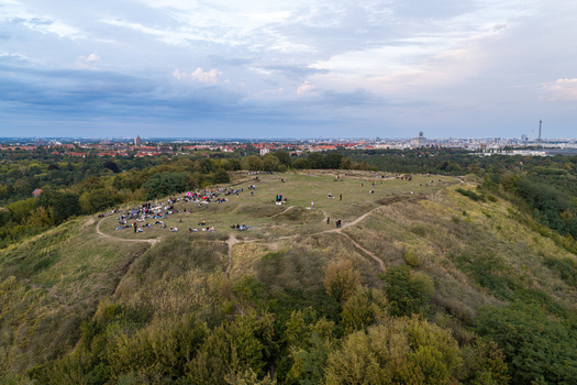 Aerial view of Drachenberg hill with people relaxing on the grassy slopes surrounded by lush trees and the distant city skyline of Berlin Berlin Germany.