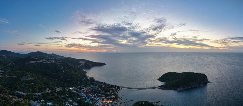 Aerial view of Ko Pha Ngan with its iconic sandbar connecting to a small island surrounded by lush hills and the calm sea at twilight in Ko Pha ngan District Surat Thani Thailand.
