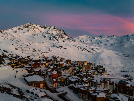 Aerial view of snow laden roofs nestle amidst the peaks kissed by the rosy glow of twilight Val Thorens Auvergne Rh&ocirc;ne Alpes France.