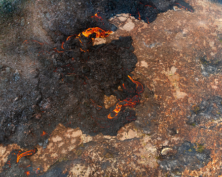Aerial view of molten lava flowing over dark volcanic rock and hardened basalt in Iceland. Aerial view of molten lava flowing over dark volcanic rock and hardened basalt in Iceland.
