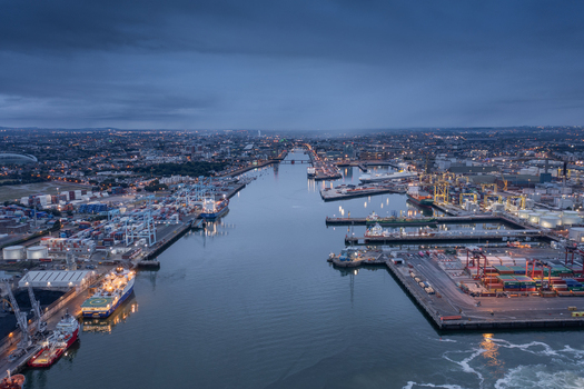 Aerial view of Dublin Port featuring cargo ships industrial cranes and city lights at twilight along the River Liffey in Dublin County Dublin Ireland. Aerial view of Dublin Port featuring cargo ships industrial cranes and city lights at twilight along the River Liffey in Dublin County Dublin Ireland.