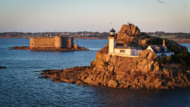 Aerial view of golden light kissing the rocky islet and lighthouse contrasting with the imposing Château du Taureau Plouezoc h Bretagne France. Aerial view of golden light kissing the rocky islet and lighthouse contrasting with the imposing Château du Taureau Plouezoc h Bretagne France.