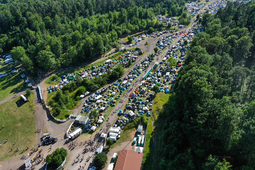 Aerial view of the crowded campsite at Eventzentrum Strohofer Geiselwind musichall with tents and people surrounded by lush green forest in Geiselwind Bayern Germany. Aerial view of the crowded campsite at Eventzentrum Strohofer Geiselwind musichall with tents and people surrounded by lush green forest in Geiselwind Bayern Germany.