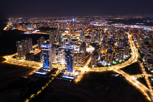 Aerial view of the illuminated cityscape of Netanya at night featuring modern high rise residential towers glowing street lights and urban infrastructure in Netanya Center District Israel. Aerial view of the illuminated cityscape of Netanya at night featuring modern high rise residential towers glowing street lights and urban infrastructure in Netanya Center District Israel.