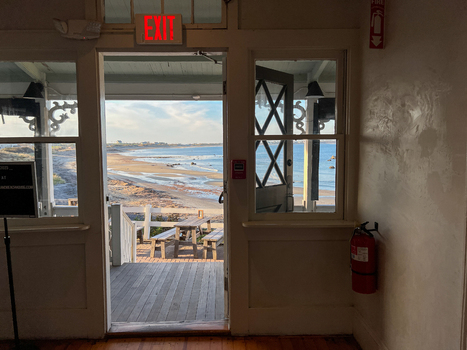 View of Block Island beach seen from an interior doorway with a wooden picnic table on the deck New Shoreham Rhode Island United States.