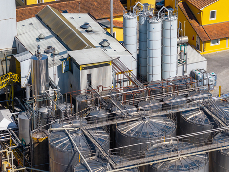 Aerial view of an industrial facility featuring stainless steel storage tanks complex piping systems and yellow buildings in Spoleto Umbria Italy. Aerial view of an industrial facility featuring stainless steel storage tanks complex piping systems and yellow buildings in Spoleto Umbria Italy.
