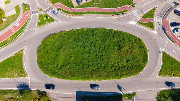Aerial view of a traffic roundabout with a central grassy island surrounded by asphalt roads road markings and bicycle paths in Mediglia Lombardy Italy. Aerial view of a traffic roundabout with a central grassy island surrounded by asphalt roads road markings and bicycle paths in Mediglia Lombardy Italy.
