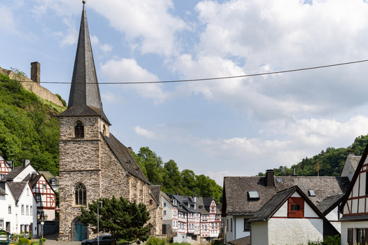 View of the historic Parish Church of the Holy Trinity and traditional half timbered houses under a blue sky in Monreal Rhineland Palatinate Germany. View of the historic Parish Church of the Holy Trinity and traditional half timbered houses under a blue sky in Monreal Rhineland Palatinate Germany.