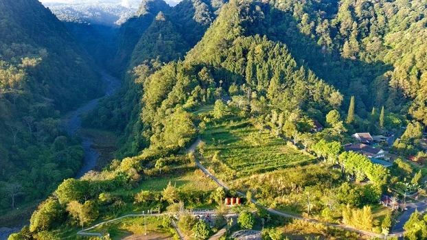 Aerial view of Kaliurang in the lush mountainous landscape with dense forests a winding river valley and green fields in Pakem Special Region of Yogyakarta Indonesia.