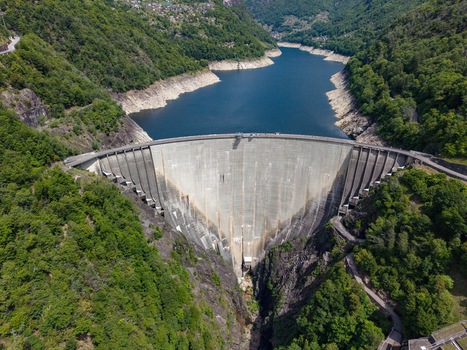 Aerial view of the massive concrete Verzasca Dam surrounded by steep forested mountains and the blue waters of Lake Vogorno in Gordola Ticino Switzerland. Aerial view of the massive concrete Verzasca Dam surrounded by steep forested mountains and the blue waters of Lake Vogorno in Gordola Ticino Switzerland.