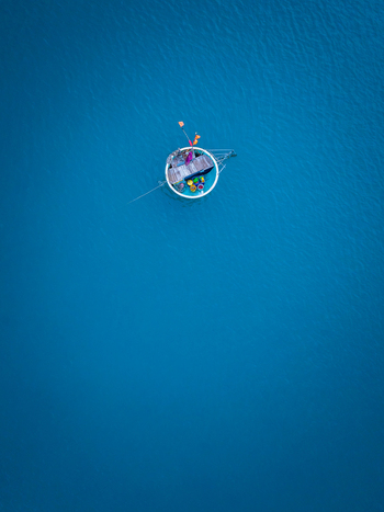 Aerial view of a traditional basket boat floating on calm blue water in Vietnam. Aerial view of a traditional basket boat floating on calm blue water in Vietnam.
