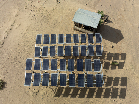 Aerial view of a solar panel array installed in a sandy desert landscape next to a small shed in Marsabit County Kenya. Aerial view of a solar panel array installed in a sandy desert landscape next to a small shed in Marsabit County Kenya.