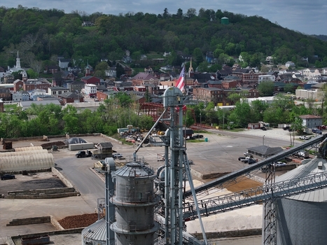 Aerial view of industrial grain silos and elevators overlooking the historic town buildings and lush green hills in Aurora Indiana United States. Aerial view of industrial grain silos and elevators overlooking the historic town buildings and lush green hills in Aurora Indiana United States.